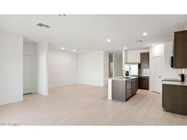 Bright open-concept living area next to a modern kitchen featuring stainless steel appliances and an island at 25464 W Fraktur Rd, Buckeye, AZ 85326