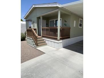 Inviting, light green home featuring a covered front porch with wood railing and stairs at 7807 E Main St # Cc-98, Mesa, AZ 85207