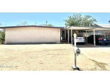Single story home with a brick facade, carport, desert landscaping and a mailbox at 1231 E Avila Ave, Casa Grande, AZ 85122