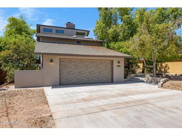 Contemporary stucco home featuring a two-car garage with a concrete driveway and mature trees in the front yard at 1419 E Las Palmaritas Dr, Phoenix, AZ 85020