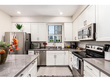 Modern kitchen with stainless steel appliances, gray countertops and white cabinetry at 2090 S Dorsey Ln # 1019, Tempe, AZ 85282