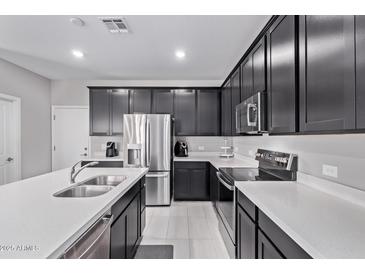 Modern kitchen featuring dark cabinets, stainless steel appliances, and a large island with quartz countertops at 2625 S Peppertree Dr # 101, Gilbert, AZ 85295
