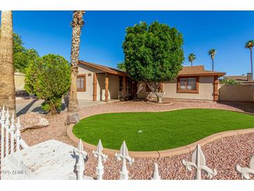 A single-story home with a charming front yard, lush lawn, and mature trees at 5649 W Holly St, Phoenix, AZ 85035
