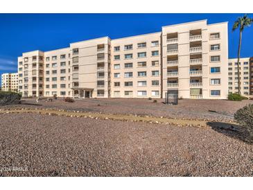 Low-angle exterior view of the apartment building showing balconies, desert landscaping, and a clear blue sky at 7920 E Camelback Rd # 609, Scottsdale, AZ 85251