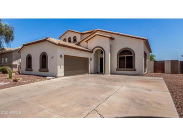 Charming single-story home features a well-manicured lawn, arched entryway, and a two-car garage at 15811 N 155Th Dr, Surprise, AZ 85374