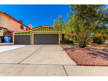 Inviting curb appeal with a green home exterior, flowering tree, three car garage and well-manicured landscaping at 2109 E Gelding Dr, Phoenix, AZ 85022