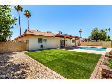 Inviting backyard featuring artificial grass, a refreshing pool, and a covered patio area at 3913 N 86Th St, Scottsdale, AZ 85251