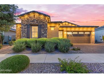 Charming stone accented home featuring an attached garage, manicured shrubs, and festive outdoor lighting at 10650 E Palladium Dr, Mesa, AZ 85212