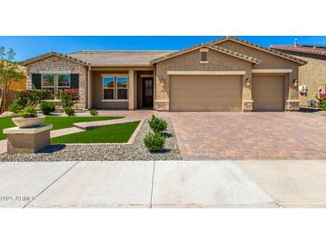 Charming single-story home with a well-manicured front yard and brick-paved driveway leading to a two-car garage at 18908 W Montebello Ave, Litchfield Park, AZ 85340