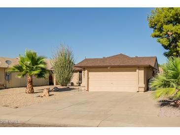 Single-story home showcasing desert landscaping, palm trees, and a two-car garage at 21061 N 33Rd Dr, Phoenix, AZ 85027
