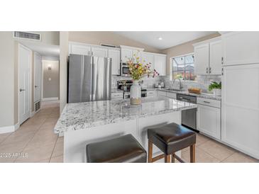 Bright kitchen featuring white cabinetry, stainless steel appliances, and a granite island with seating at 3844 E Shomi St, Phoenix, AZ 85044