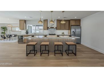Open concept kitchen with light wood cabinets, stone countertops, and modern pendant lighting at 5028 W Shangri La Rd, Glendale, AZ 85304