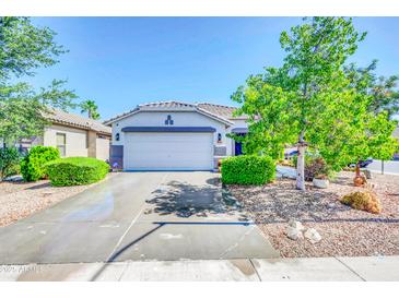 Charming single-story home featuring a well-manicured front yard with lush landscaping and a two-car garage at 46068 W Guilder Ave, Maricopa, AZ 85139