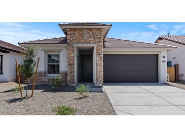 Stylish single-Gathering home featuring stone accents and a gray garage door for a modern, appealing facade at 7421 S 76Th Ln, Laveen, AZ 85339