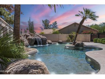 Backyard pool with rock waterfall feature and lush desert landscaping for a relaxing outdoor oasis at 9412 S Palm Dr, Tempe, AZ 85284