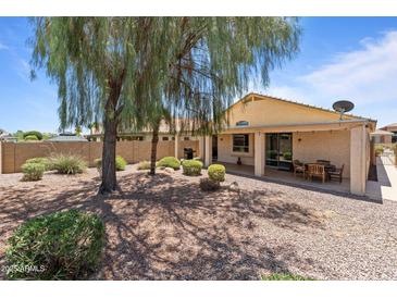 Expansive backyard featuring gravel landscaping, covered patio, and mature trees, creating a relaxing outdoor space at 18066 W Weatherby Dr, Surprise, AZ 85374