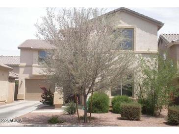 Lovely home featuring a two-car garage, lush landscaping, and a well-maintained lawn at 21050 E Munoz St, Queen Creek, AZ 85142