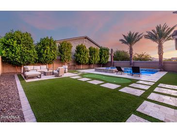 Spacious backyard with pool, patio seating, putting green, and artificial turf at 14481 W Via Del Oro --, Surprise, AZ 85379