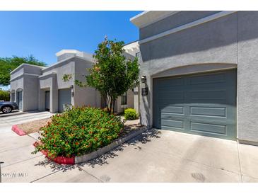 Contemporary townhouse exterior with gray facade, private garages, and colorful, mature landscaping at 295 N Rural Rd # 160, Chandler, AZ 85226