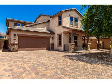 Two-story home featuring stucco siding, a covered porch, paver driveway, and a two-car garage at 4277 N 180Th Ln, Goodyear, AZ 85395