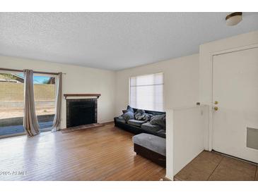 Bright living room with hardwood floors, fireplace, and sliding glass door to patio at 12842 S Wakial Loop, Phoenix, AZ 85044