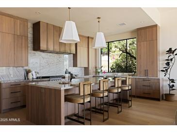 Modern kitchen featuring wood cabinetry, marble countertops, a large island, and pendant lighting fixtures at 12887 N 135 St, Scottsdale, AZ 85259