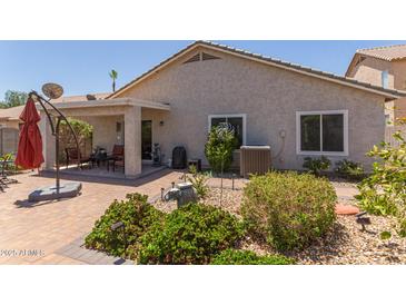 An outdoor patio includes brick pavers, an umbrella, and comfortable seating for relaxing and entertaining at 1628 E Aspen Ave, Buckeye, AZ 85326