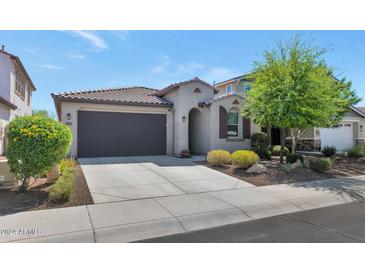 Charming single-story home with a tile roof, neutral stucco and a dark garage door at 22353 N 99Th Ln, Peoria, AZ 85383