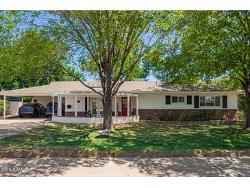 Charming home with a well-manicured lawn, mature tree, and inviting red front door at 4238 E Mitchell Dr, Phoenix, AZ 85018