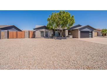 Charming single-story home with xeriscaped yard, complemented by mature tree and modern garage door at 6719 S Hardy Dr, Tempe, AZ 85283