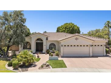 Attractive single-story home showcasing a three-car garage, tile roof, landscaped yard, and welcoming front entry at 7032 N 2Nd Ave, Phoenix, AZ 85021
