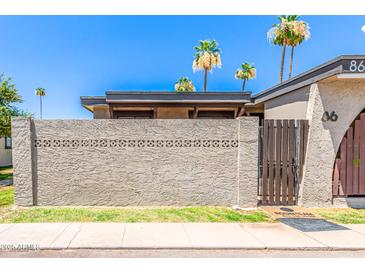 A charming home is adorned with decorative cinder block and a gated wooden fence entry, enhancing curb appeal at 830 S Dobson Rd # 86, Mesa, AZ 85202