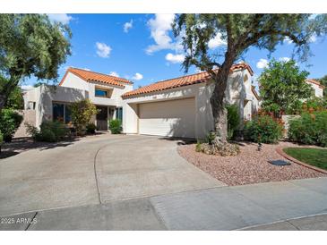 Charming home featuring a red tile roof and a two-car garage with well-maintained landscaping at 10068 E San Salvador Dr, Scottsdale, AZ 85258