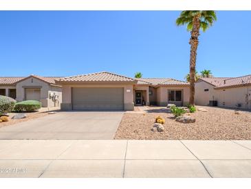 Charming single-story home featuring a desert landscape, two-car garage, and a beautiful palm tree on a sunny day at 16354 W Labyrinth Ln, Surprise, AZ 85374