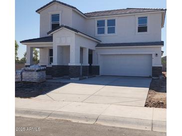 Two-story home featuring neutral stucco, stone accents, covered porch, and a two car garage at 2309 S 125Th Dr, Avondale, AZ 85323