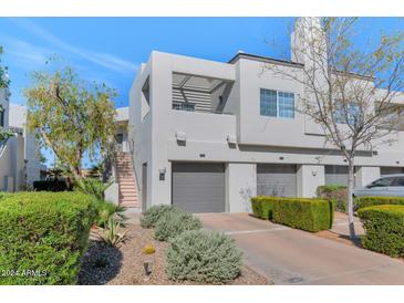 Modern townhouse showcasing a three-car garage and landscaped front yard on a sunny day at 7710 E Gainey Ranch Rd # 206, Scottsdale, AZ 85258