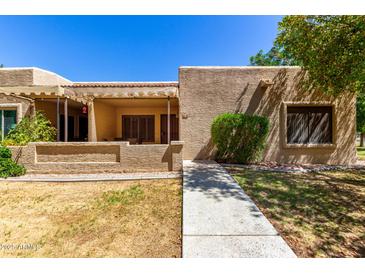 Inviting front exterior featuring a covered patio, neutral stucco, and desert landscaping at 14300 W Bell Rd # 6, Surprise, AZ 85374