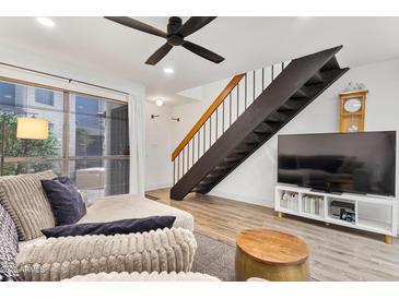 Bright living room features modern ceiling fan, wood floors, and open staircase at 2946 N 14Th St # 3, Phoenix, AZ 85014