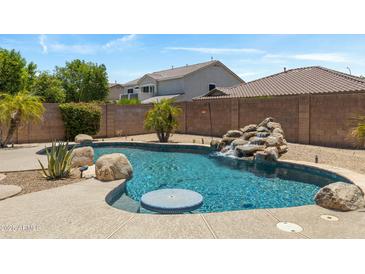 Inviting pool with rock waterfall feature surrounded by desert landscaping in a private backyard setting at 4093 E Westchester Dr, Chandler, AZ 85249