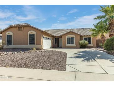Charming single-story home with a well-manicured yard and a long driveway leading to a two-car garage at 909 E Harwell Rd, Phoenix, AZ 85042