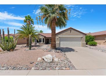 Charming home featuring desert landscaping, palm trees and a two-car garage at 15971 W Indigo Ln, Surprise, AZ 85374