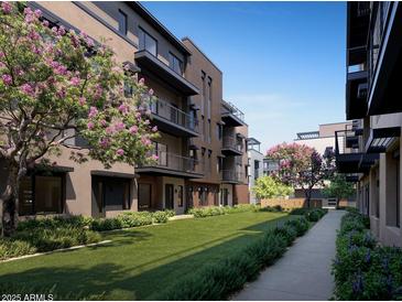 Modern condos with balconies overlook a manicured green lawn and walkway lined with blooming flowers and lush greenery at 19360 N 73Rd St # 1069, Scottsdale, AZ 85255