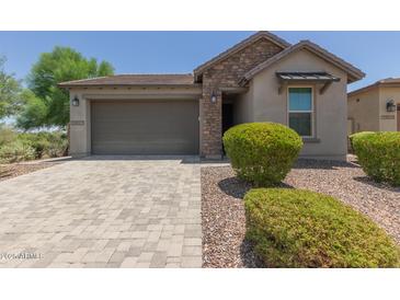 Charming single-story home featuring a stone facade, lush landscaping, and a paved driveway leading to the garage at 29007 N 120Th Dr, Peoria, AZ 85383
