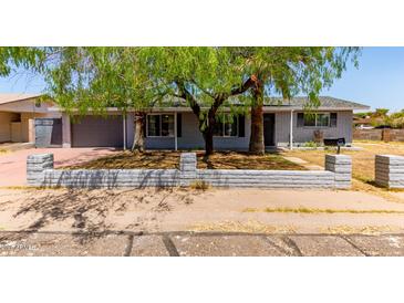 Charming single-story home with mature trees and a low brick wall enhancing the curb appeal at 17401 N 16Th Ave, Phoenix, AZ 85023