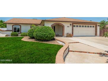 Charming home exterior featuring a well-manicured lawn, arched entry and attached two-car garage at 18820 N 33Rd Ave, Phoenix, AZ 85027