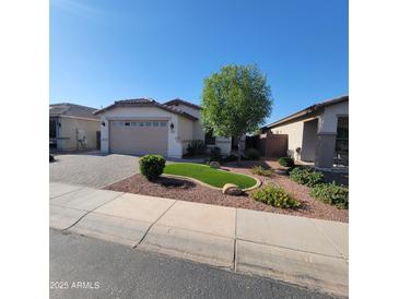 Charming home featuring well-manicured landscaping, green turf, and a spacious two-car garage at 1352 W Spine Tree Ave, Queen Creek, AZ 85140