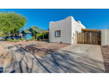 View of a quaint single-story home featuring a gravel yard and a covered parking area on a sunny day at 1409 E Apollo Rd, Phoenix, AZ 85042