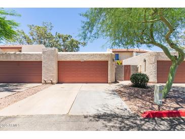 Exterior view of garage with red doors, desert landscaping, and neutral stucco at 1822 S River Dr, Tempe, AZ 85281
