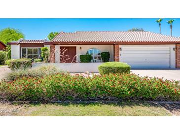 Well-maintained home featuring desert landscaping with green grass, red flowers and a red tile roof at 333 E Caribbean Ln, Phoenix, AZ 85022