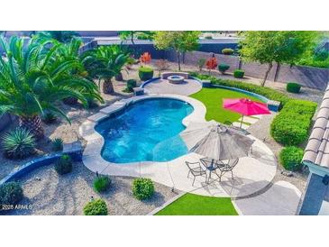 Backyard oasis with a sparkling pool, patio seating, lush landscaping and a charming fire pit for outdoor entertaining at 6731 S 37Th Dr, Phoenix, AZ 85041